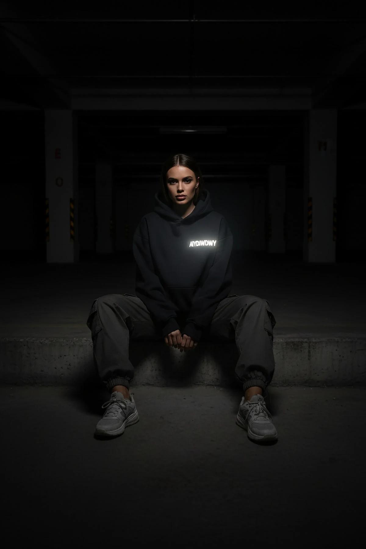 Reflective glow-in-the-dark hoodie black front view with custom text logo illuminated in dark setting