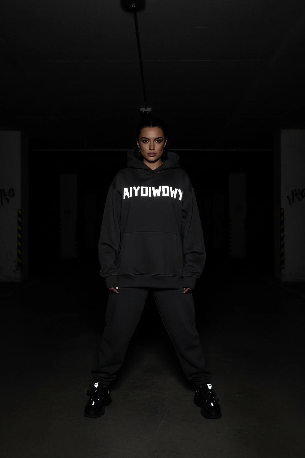 Reflective glow-in-the-dark hoodie black oversized fit with bold custom text front view in dark setting