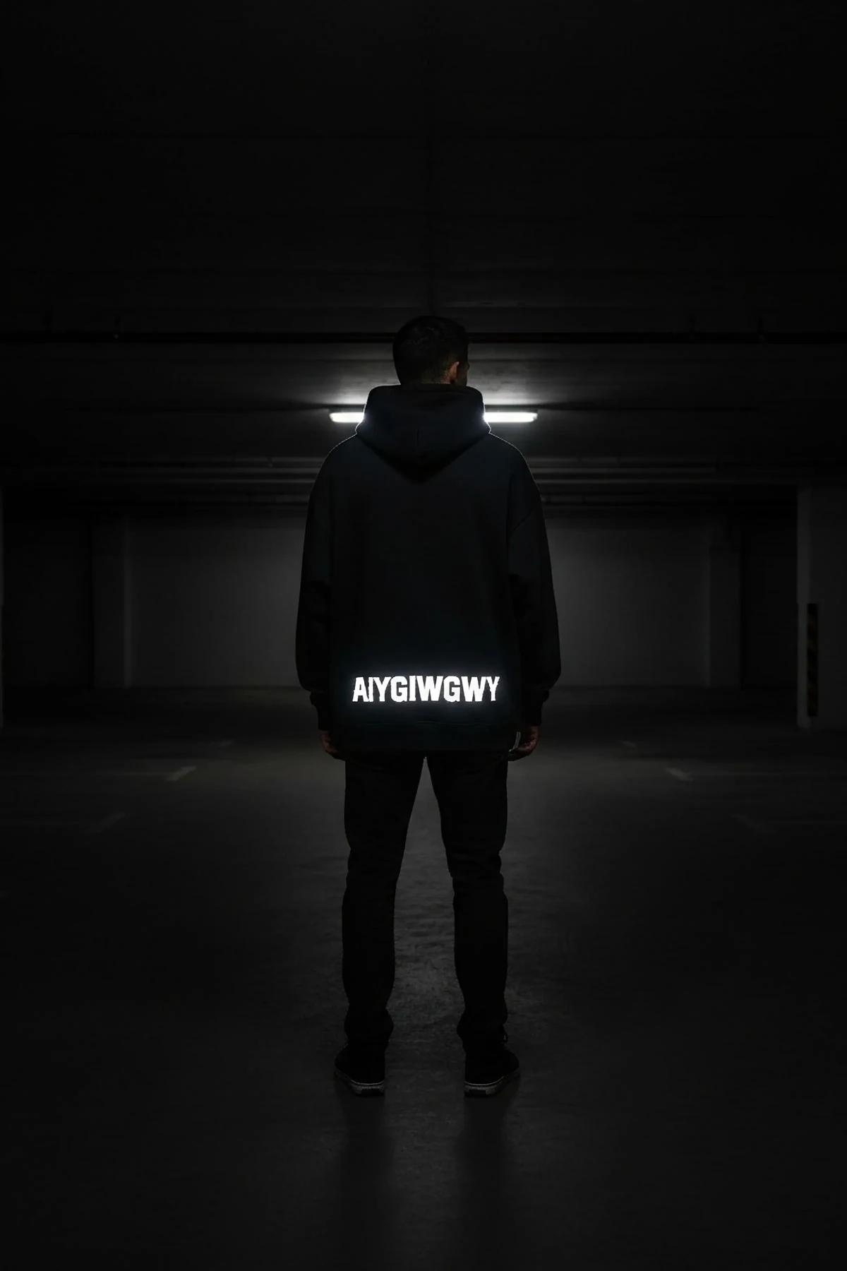Reflective glow-in-the-dark hoodie black back view with illuminated custom text AYGIWGWY in dark setting