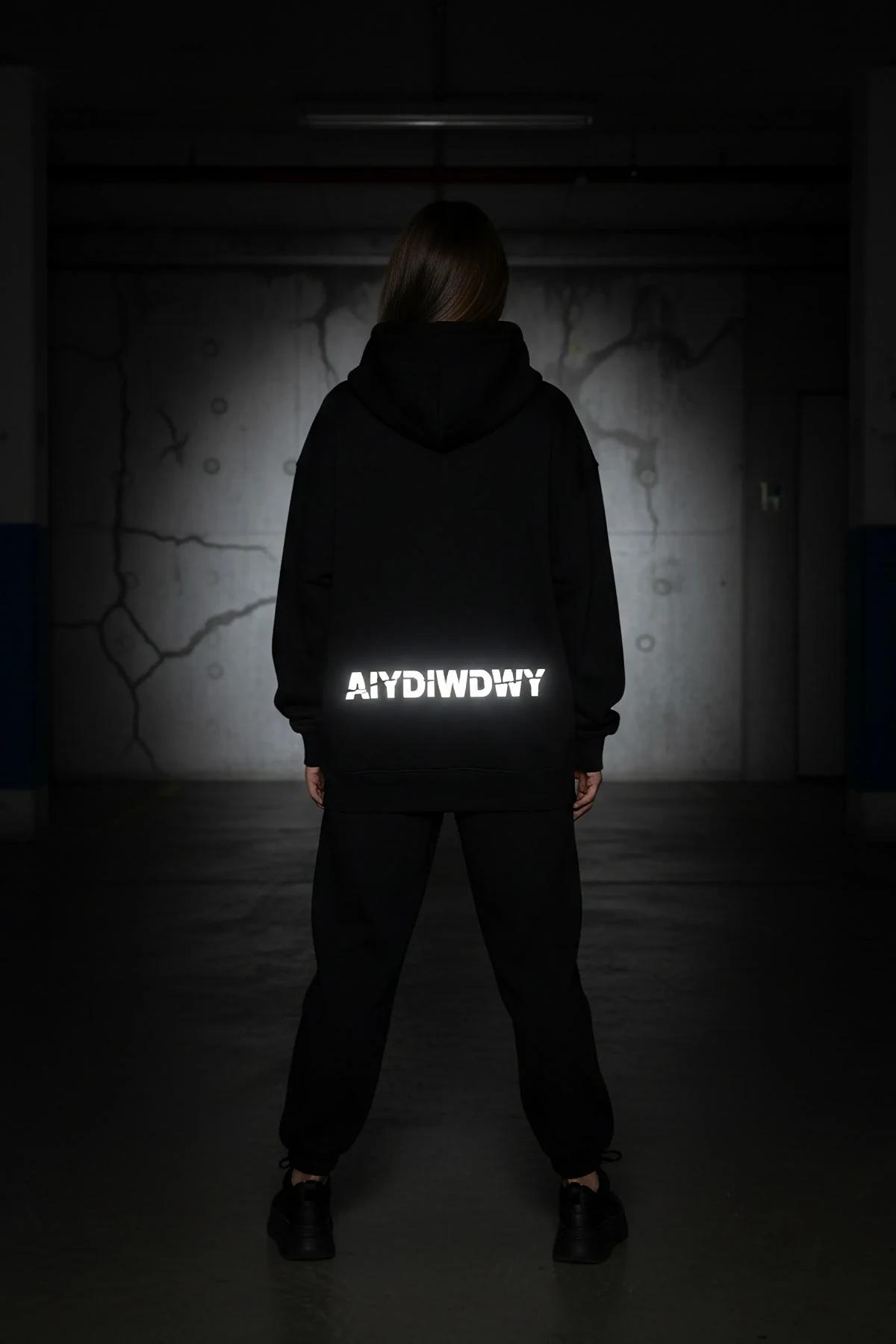 Reflective glow-in-the-dark black hoodie with custom text back view in dark setting