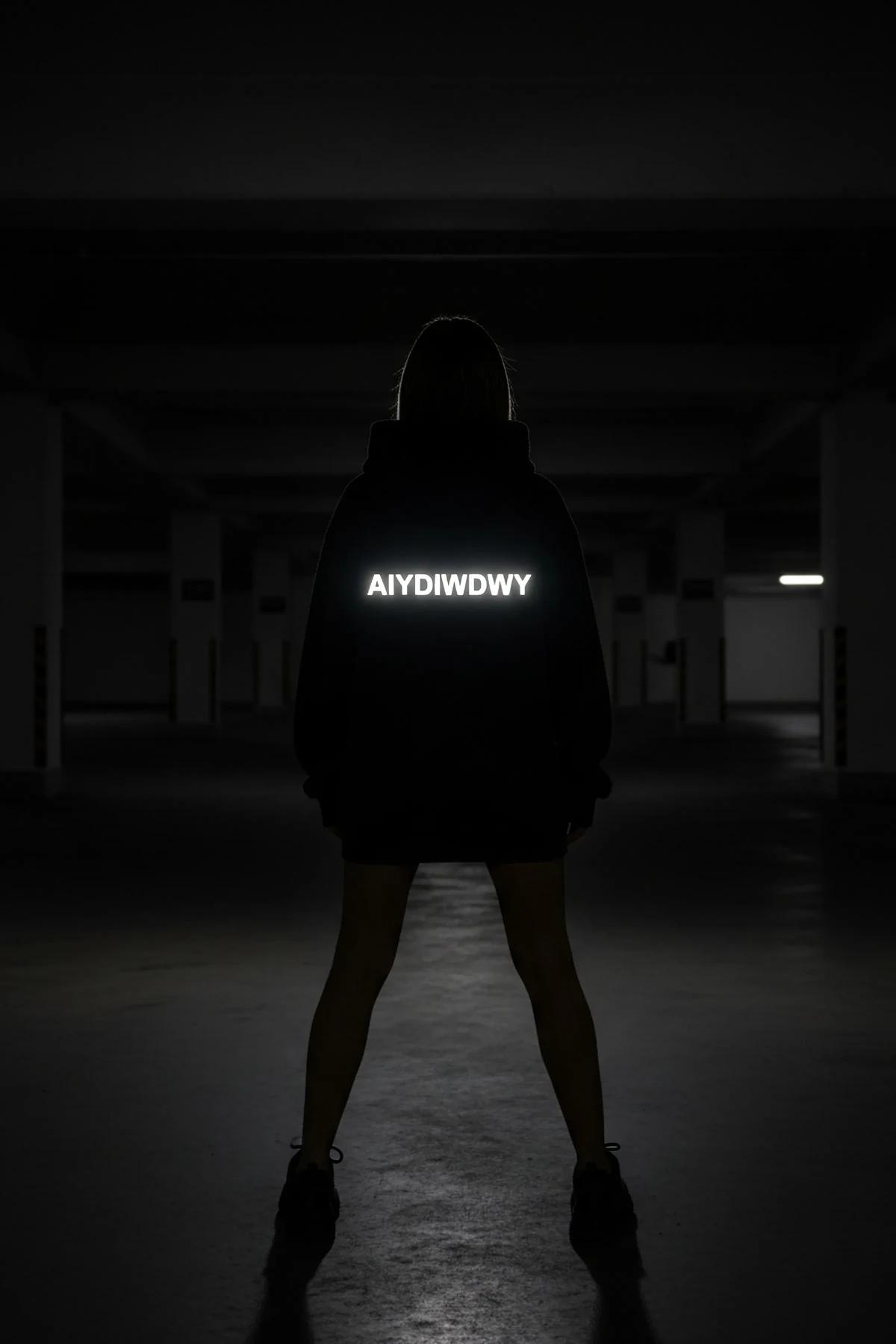 Reflective glow-in-the-dark black hoodie with custom text back view in dark setting