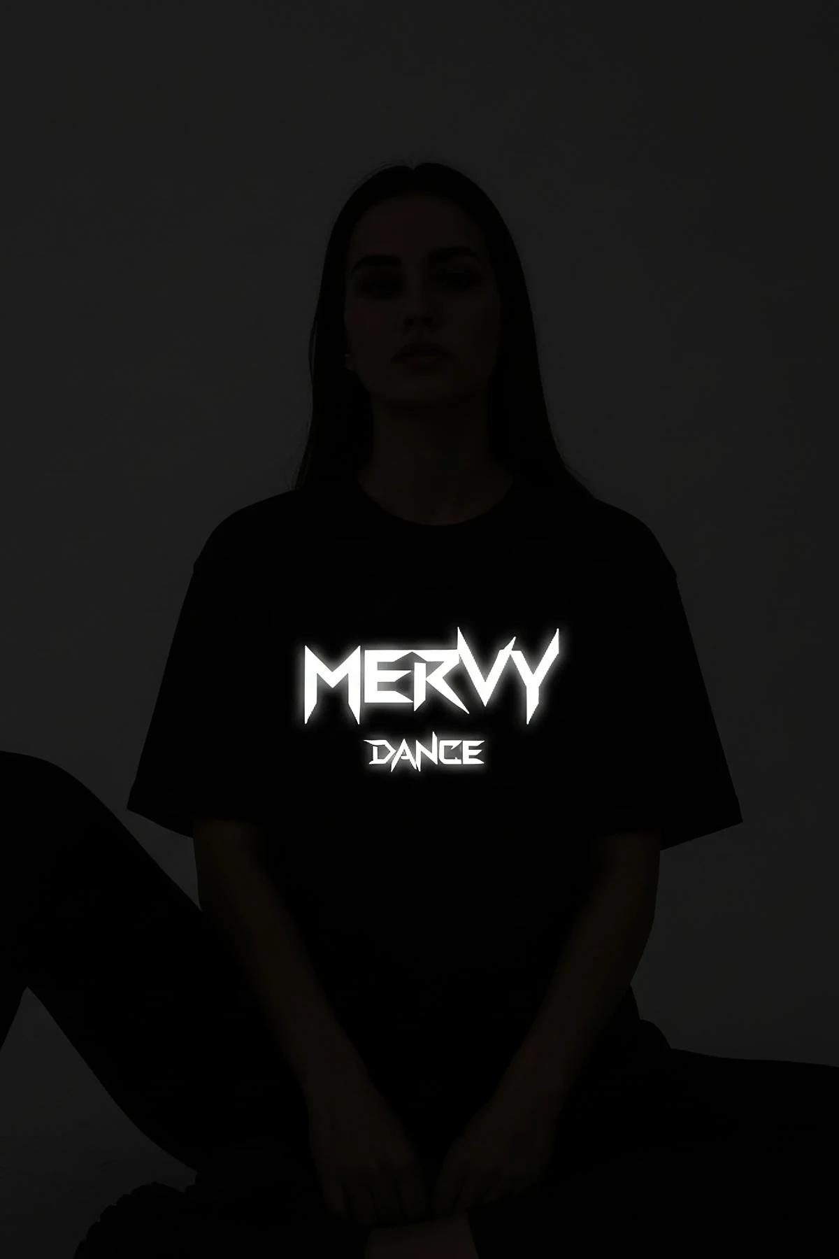 Dark grey t-shirt with bright reflective 'MERVY DANCE' graphic worn by a person, front view