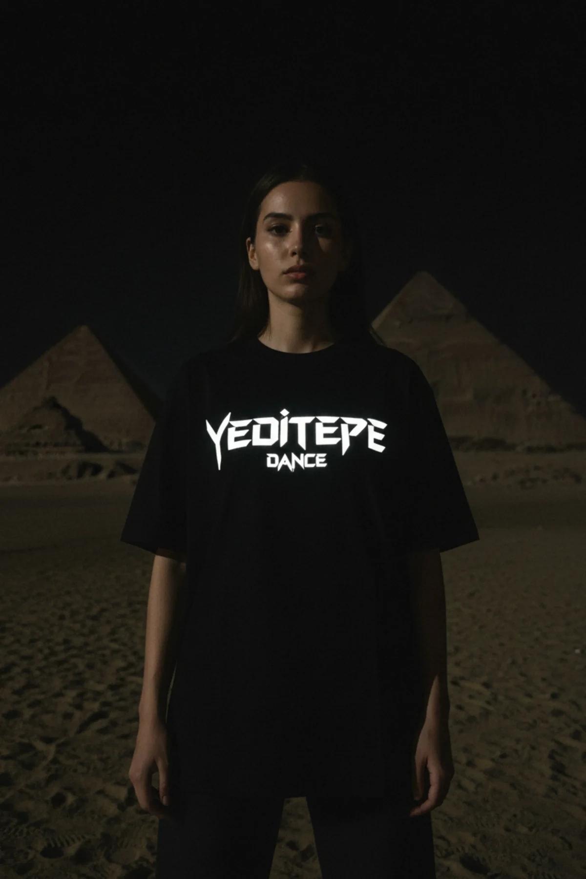 Black cotton t-shirt with a bold white reflective graphic print of 'YEDITEPE DANCE' in the center, worn by a person standing 