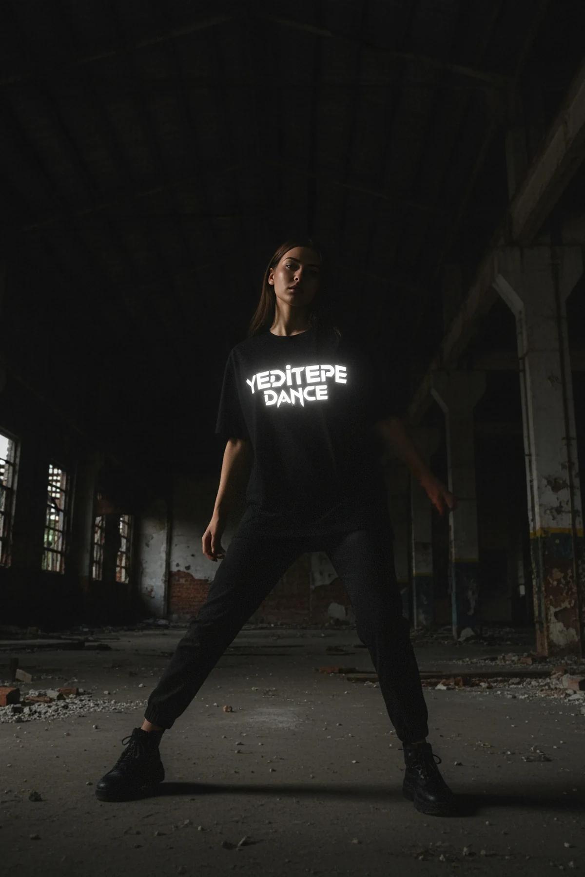 Black cotton t-shirt with a bold white reflective graphic print of 'YEDITEPE DANCE' in the center, worn by a person standing 