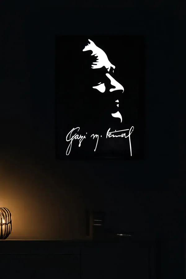 Siyah zemin üzerinde beyaz reflektörlü Atatürk silüeti ve Gazi M. Kemal imzalı dikey duvar tablosu, karanlık oda ortamı