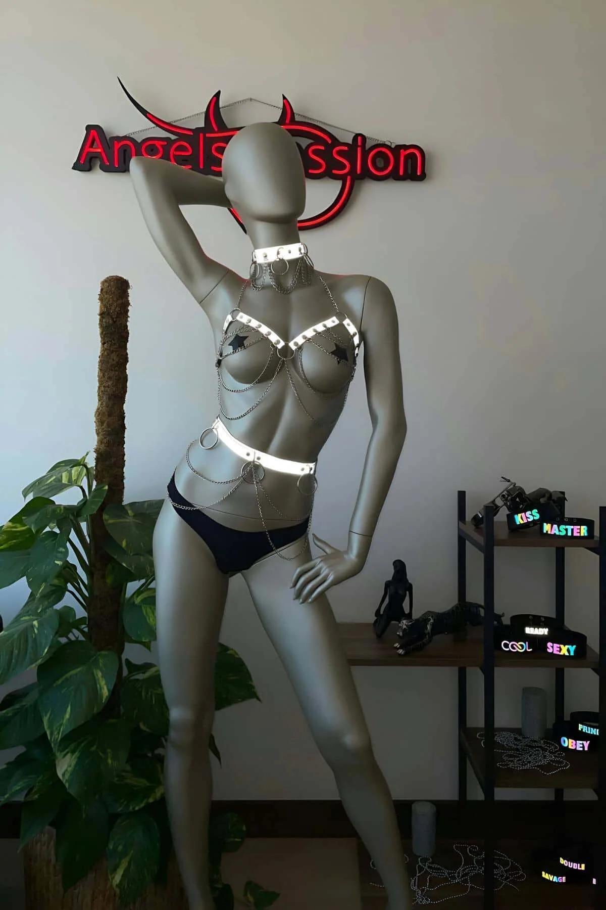 White reflective chain body harness with studded choker and draped silver-tone chains on mannequin