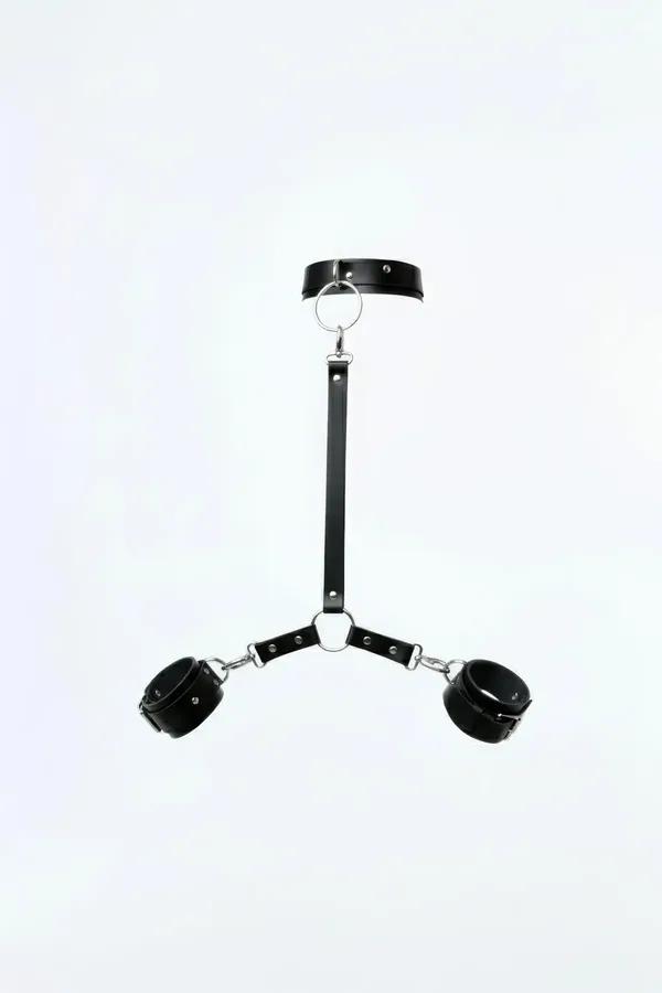 black faux leather tri-point harness with neck collar silver O-ring and two padded wrist cuffs on white background
