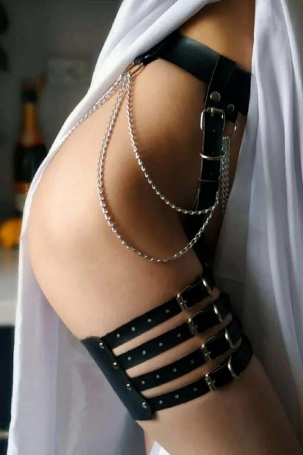 Black faux leather garter harness with four silver buckle cage straps and three draped silver chains on thigh