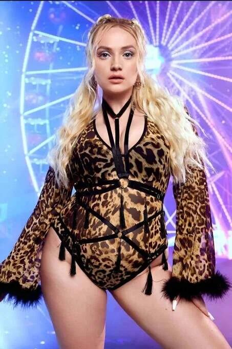 Black geometric strap body harness with gold O-rings and tassel ends worn over leopard print bodysuit