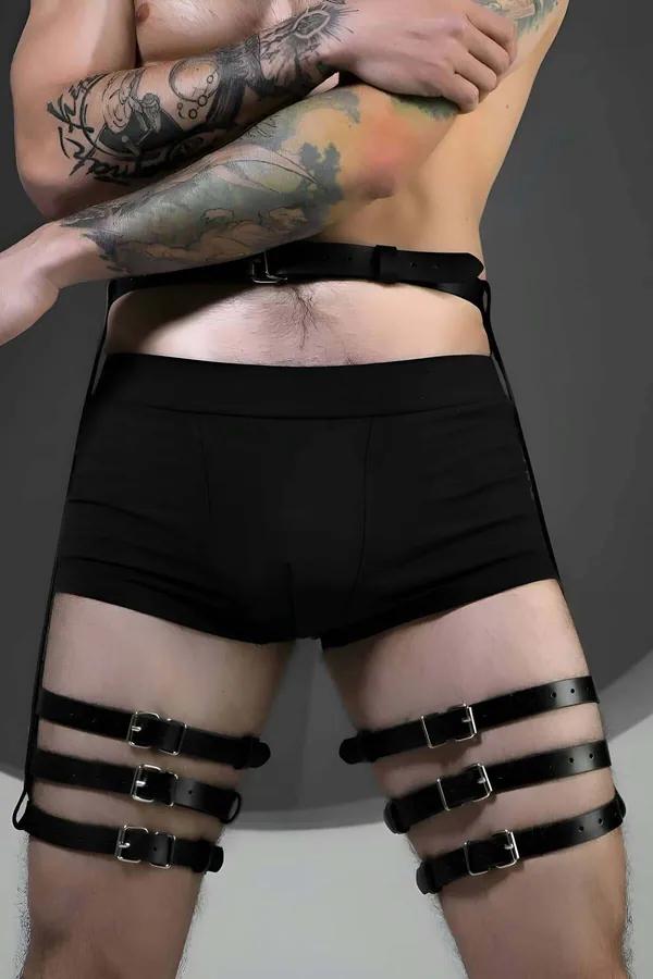 black faux leather adjustable thigh and waist harness with triple silver buckle straps worn by man over black shorts